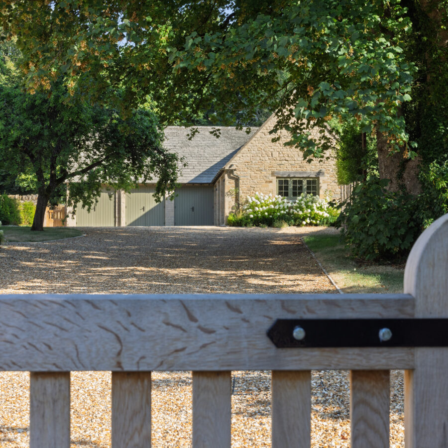 Timber driveway gate with the sloping gravel driveway visible beyond