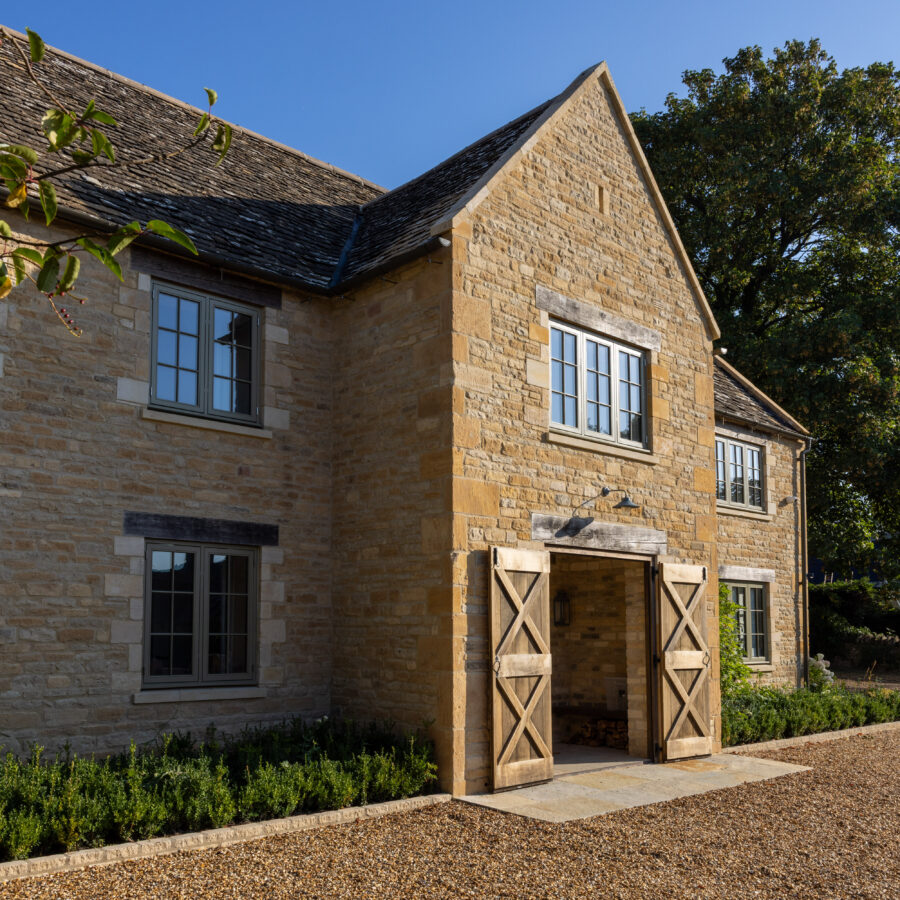 Cotswold stone country house with warm limestone walls beside a gravel driveway